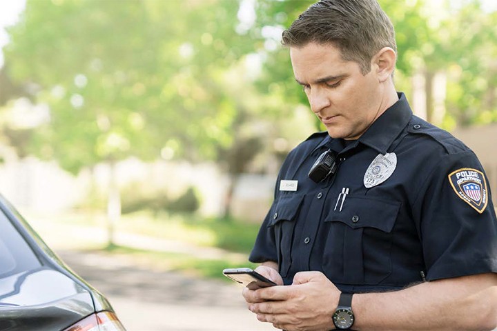 Tile | Police officer using smartphone outdoors